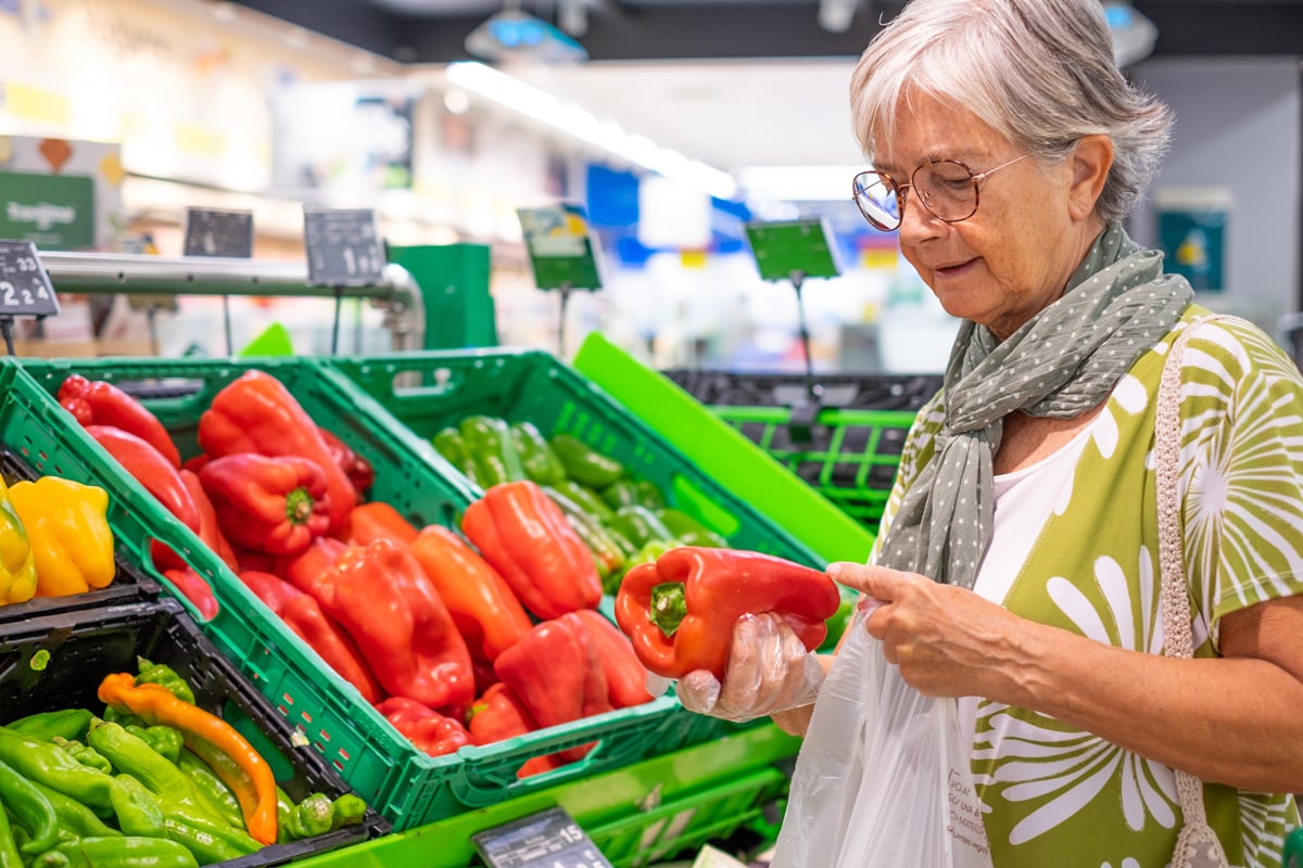 Women shopping in a social supermarket holding a capsicum Women shopping in a social supermarket holding a capsicum